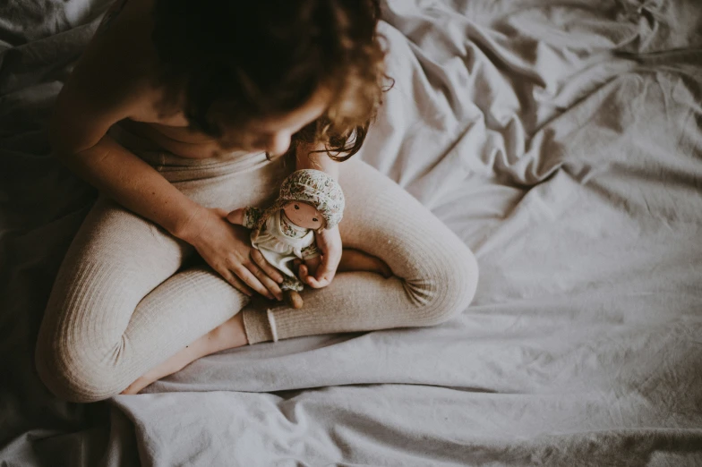 a woman holds her baby while she lays on a bed