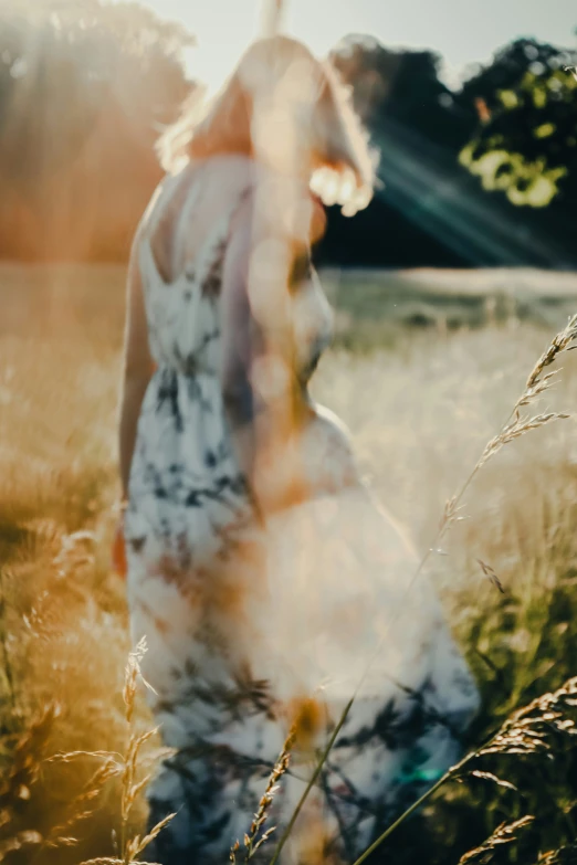 a woman in white dress walking through tall grass