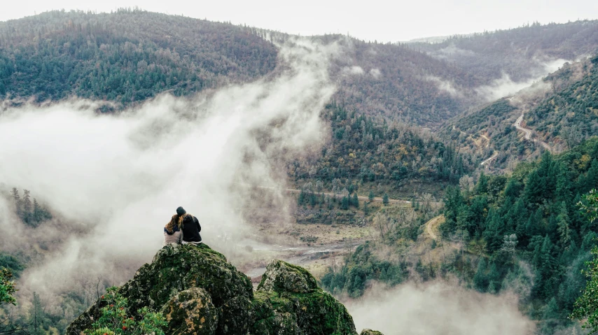 a couple sitting on top of a hill with their arms crossed