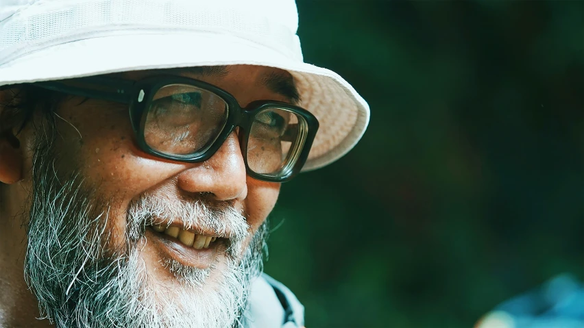 a man wearing glasses and a white hat smiling