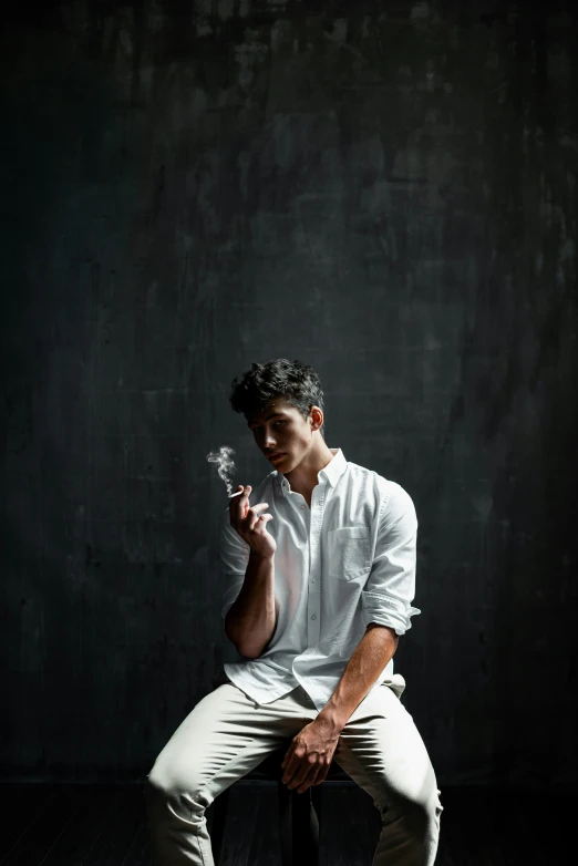 a man in white is sitting and smoking a cigarette