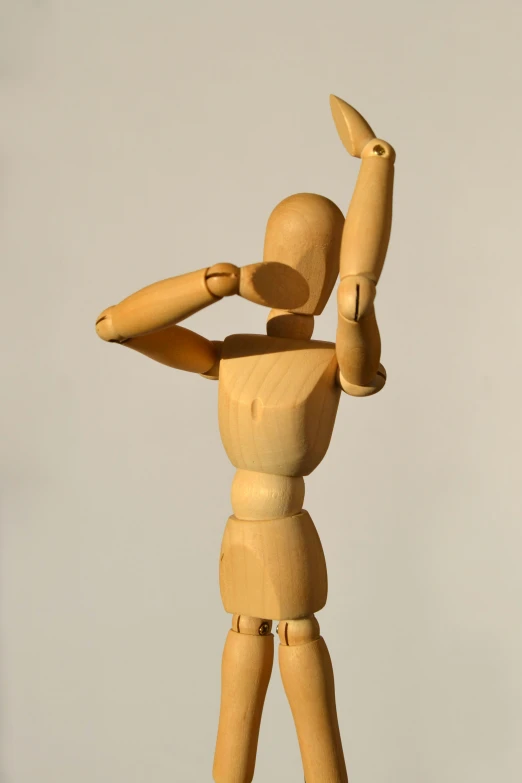 a small wood toy is standing tall, and holding a ball in one hand