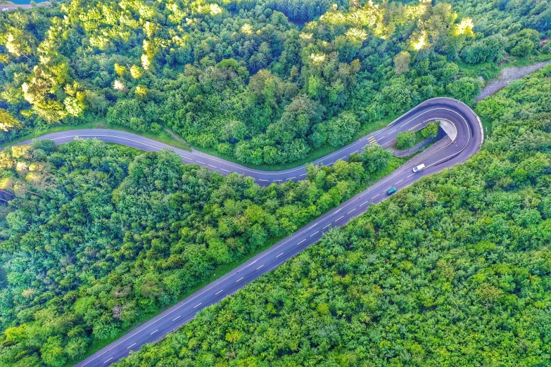 aerial view of a winding road surrounded by lush green mountains