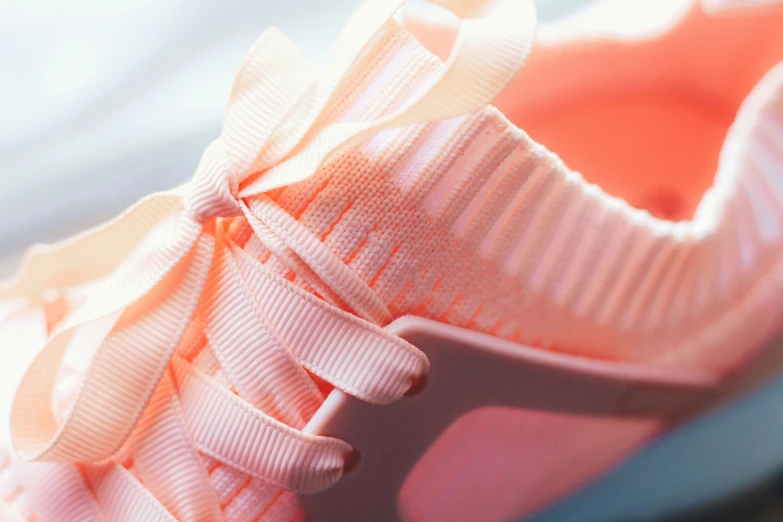 an up close po of a pink sneaker with a bow