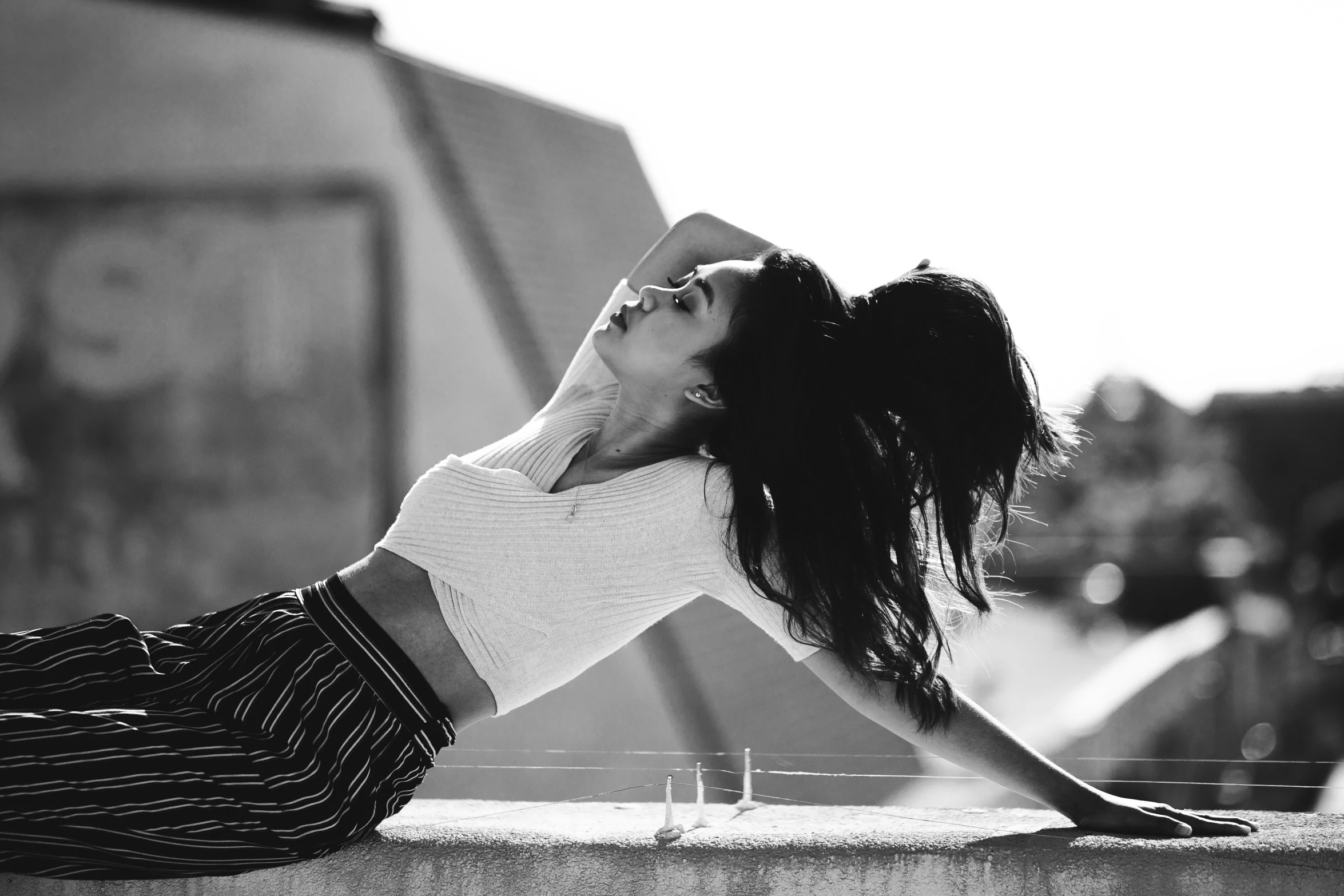 a woman sitting on top of a cement wall with her eyes closed