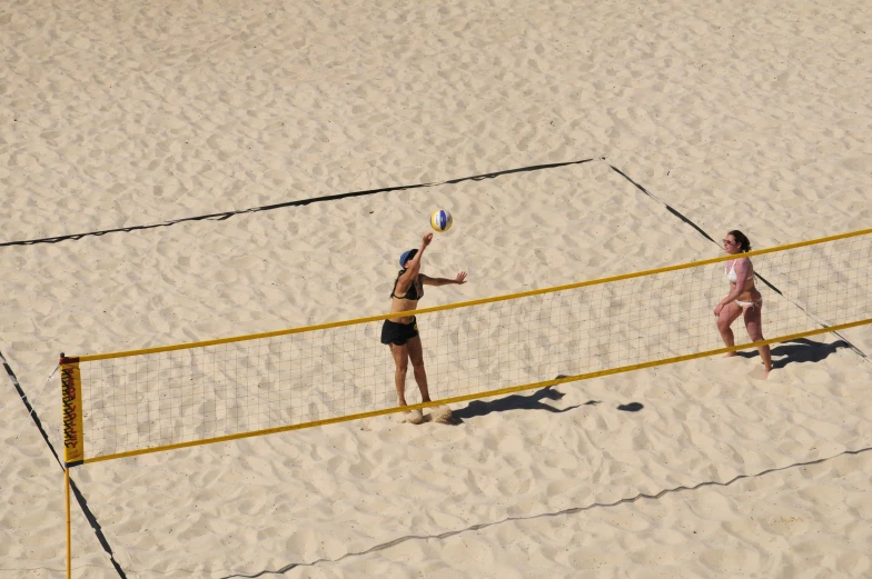 two women playing beach volleyball on the sand