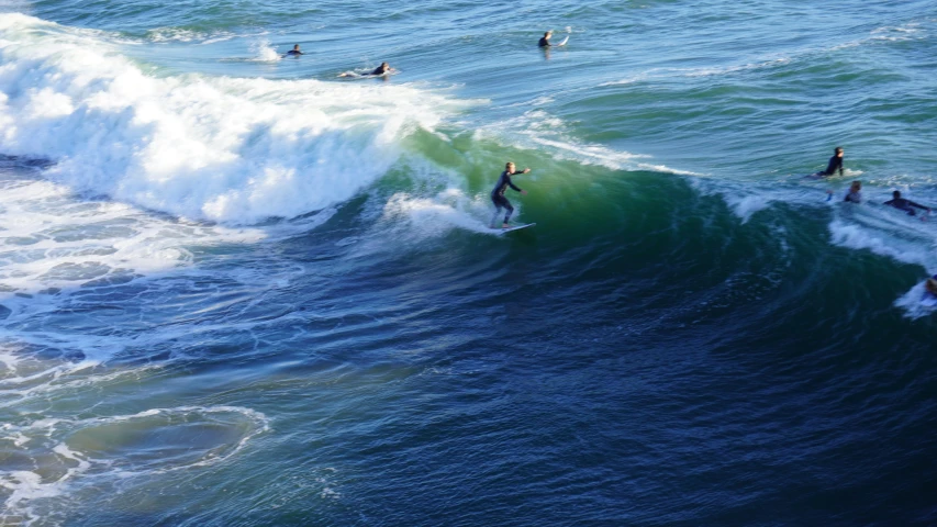 four people are surfing a large wave on the ocean