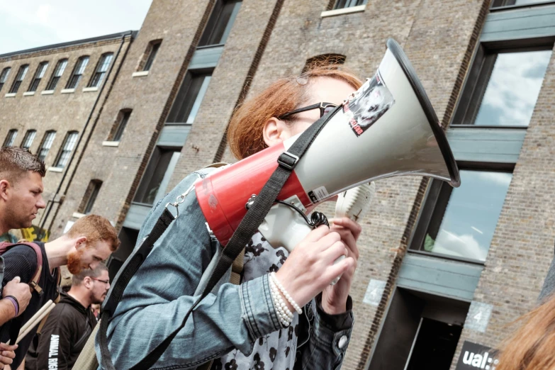 a woman wearing glasses holding a red and white megaphone