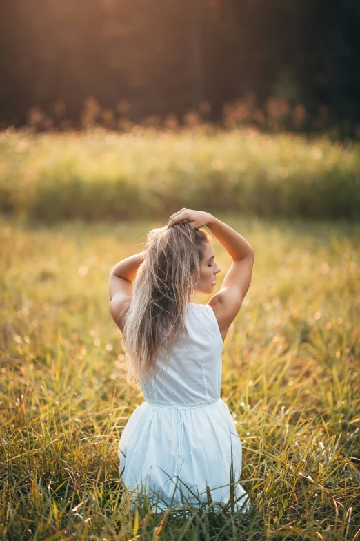 a beautiful young woman sitting in a field