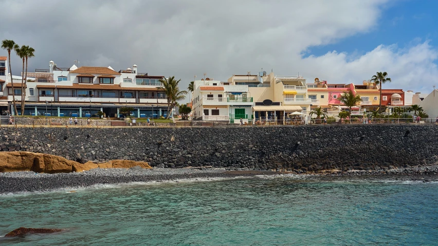 the ocean next to the beach with lots of buildings and trees