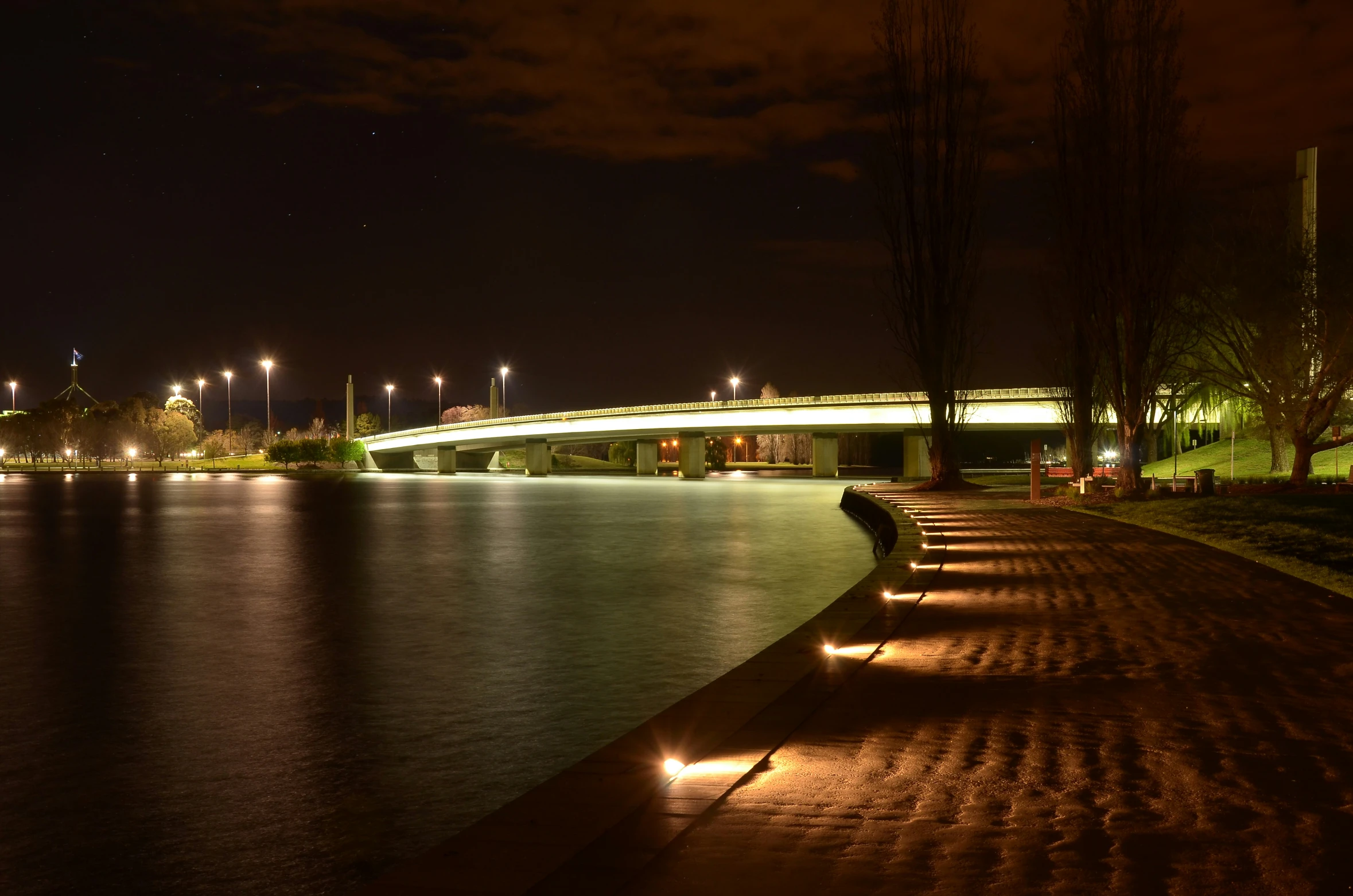 benches sitting on the water edge with city lights