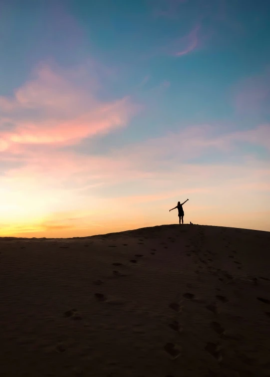 the silhouette of a man on a hillside during sunset