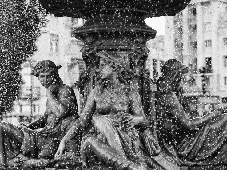 two statues sitting in the snow next to a fountain