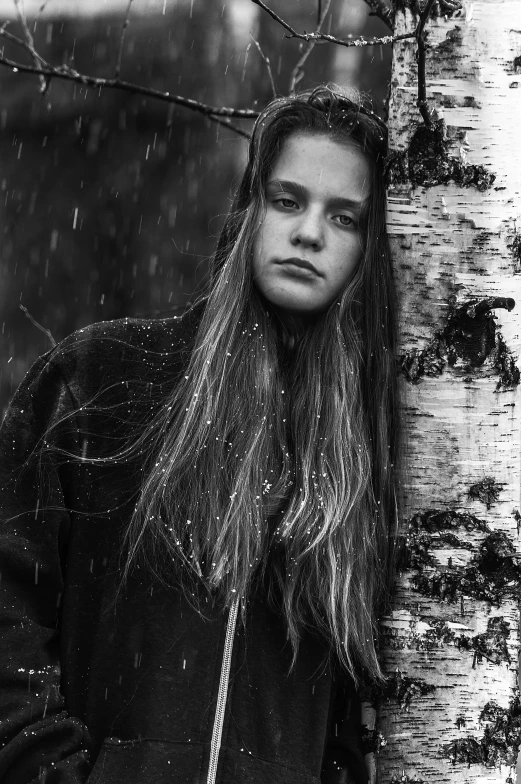 black and white image of a woman leaning against a tree