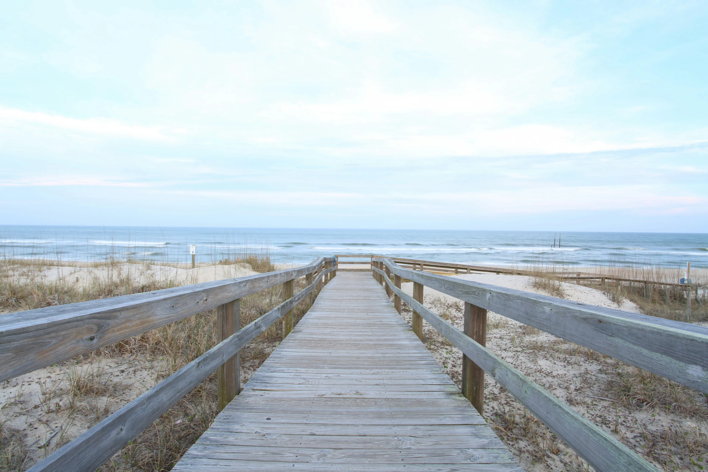 a boardwalk on the sand in front of a sandy beach