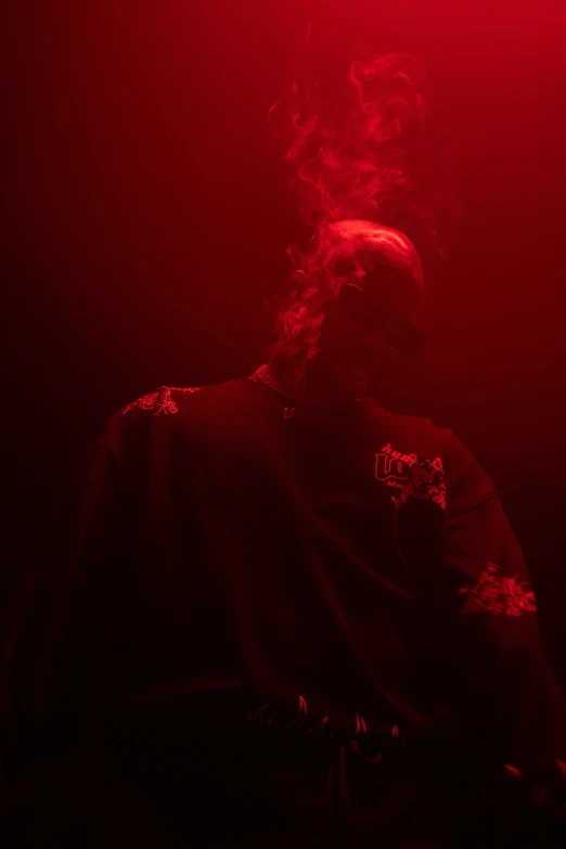 a man in a suit with a beard is seated under red light