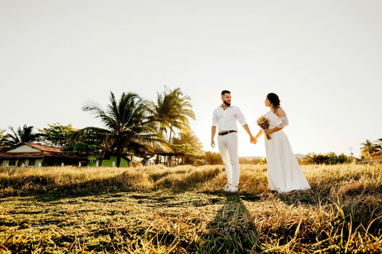 a man and woman standing in a field holding hands