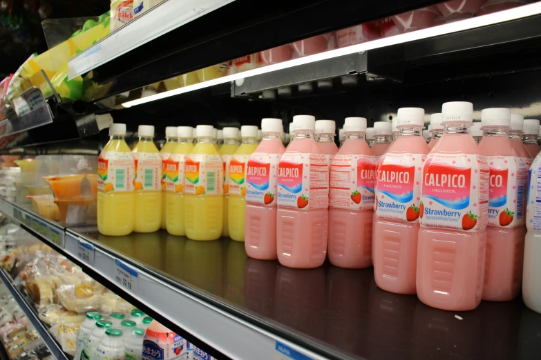many bottles of juice sit on a shelf in a grocery store