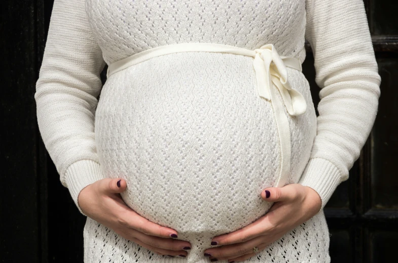 a pregnant woman with a white top and white pants