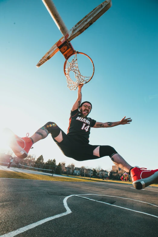 a man holding a basketball up high over the top of a basketball hoop