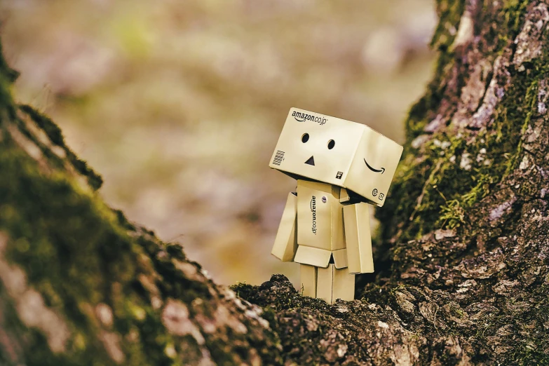 a brown paper doll standing on top of a tree trunk