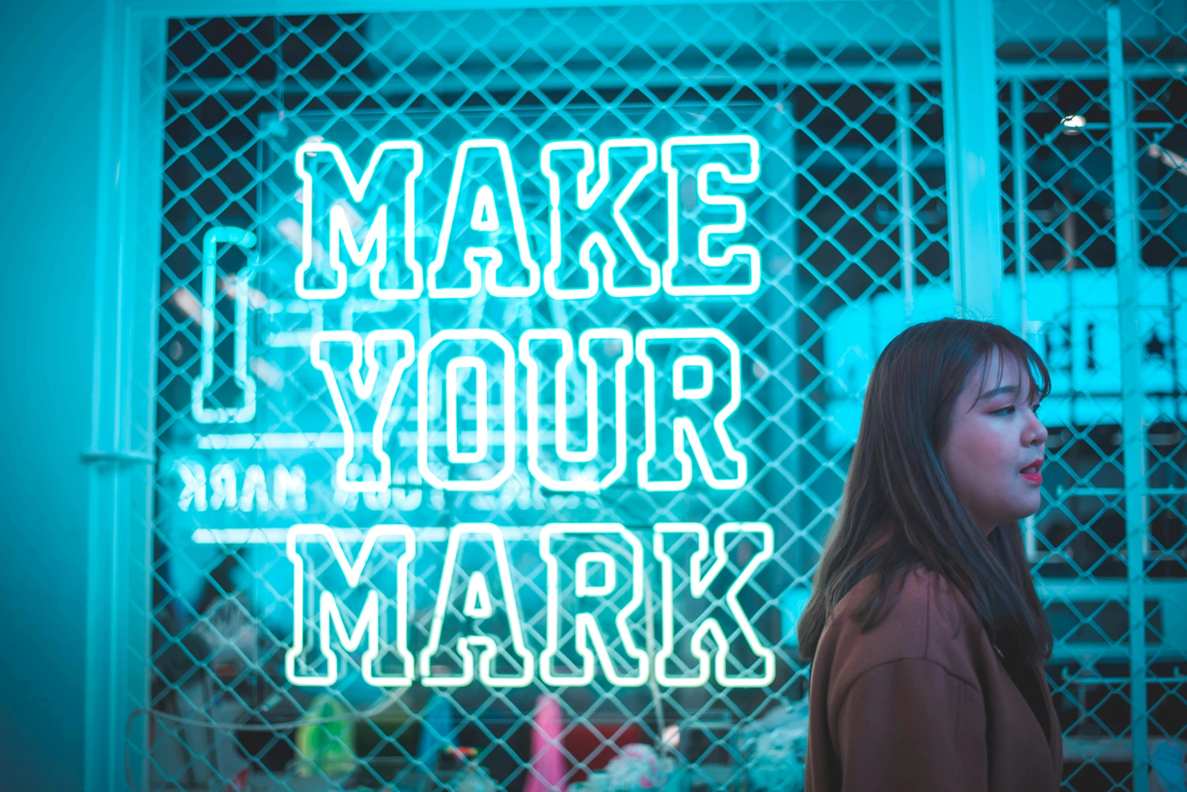 a woman standing by a neon sign with words written on it