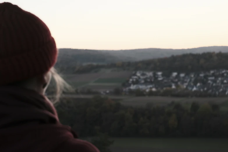 the woman looks out at the hills in the distance