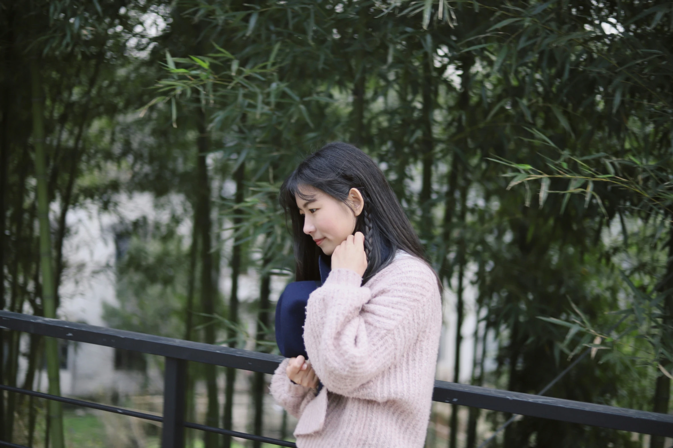 a woman leaning on a fence talking on her cell phone