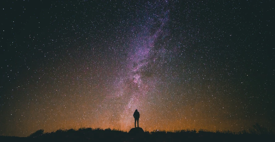 man standing on the ground looking at the night sky