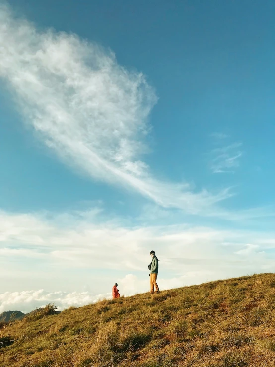 two people walking up a hill with a dog