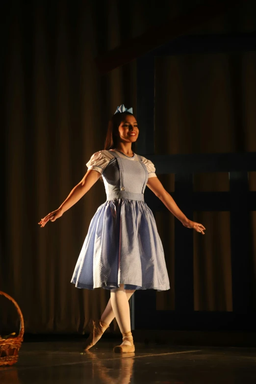 a little girl in blue and white dress on stage
