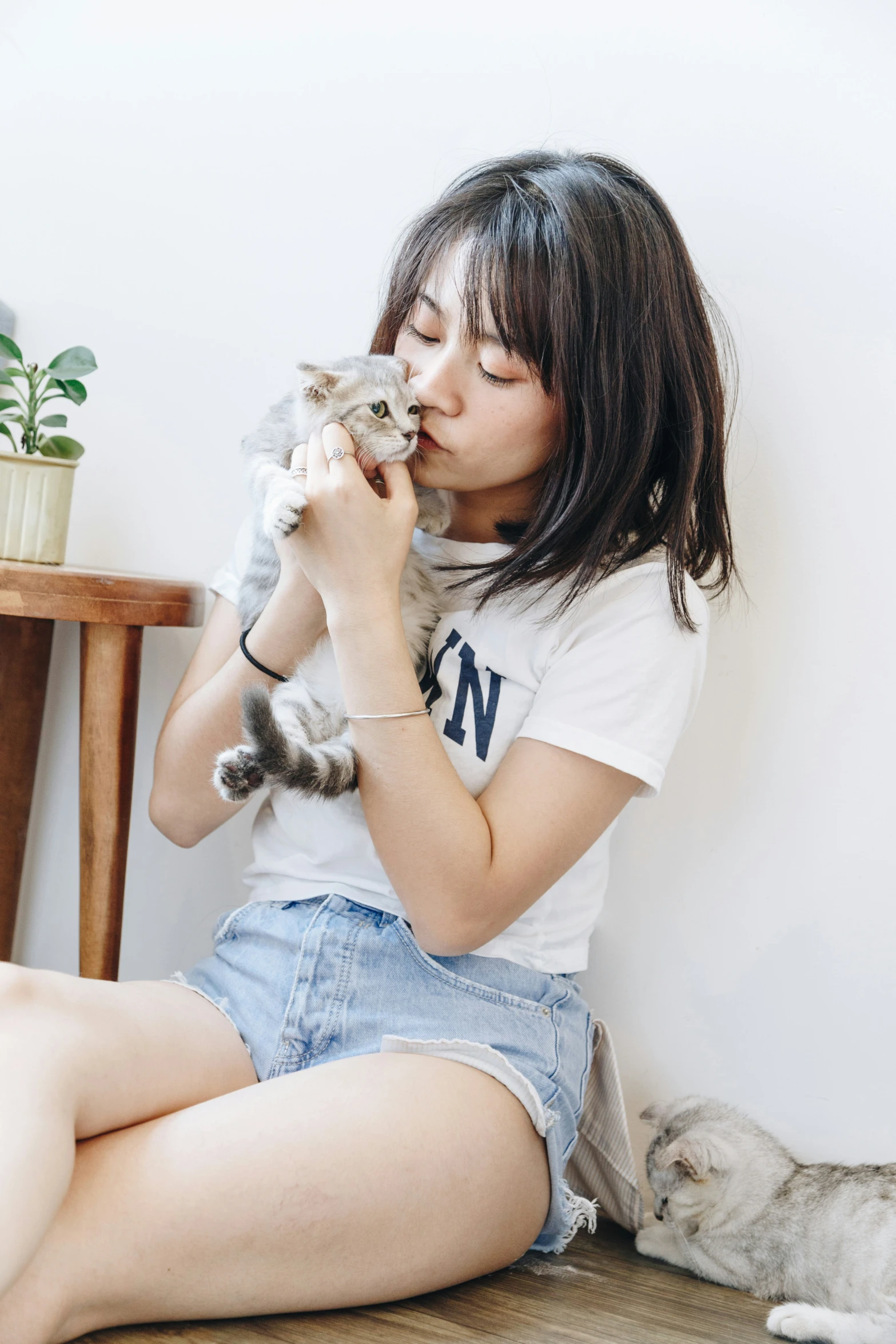 a lady with her hand on her kitty that is sitting by the floor