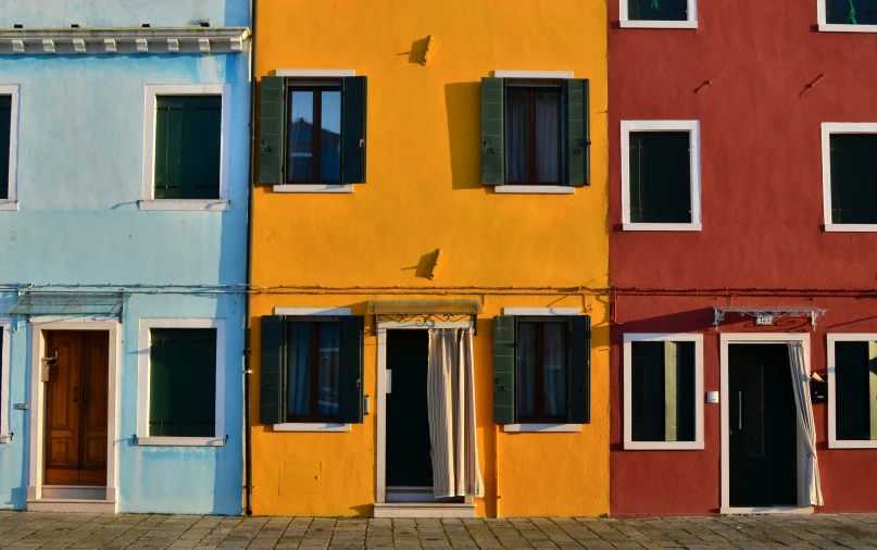 three different colors of a building with open windows