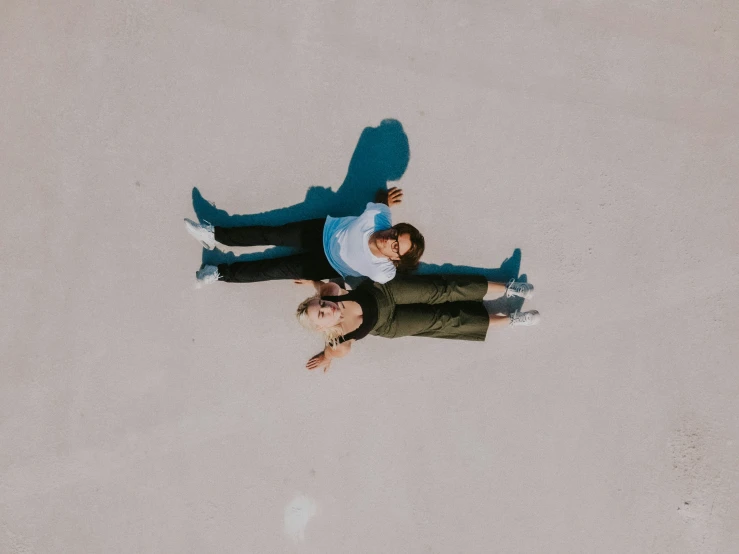 an overhead s of two young people in their sweaters looking up at the sky