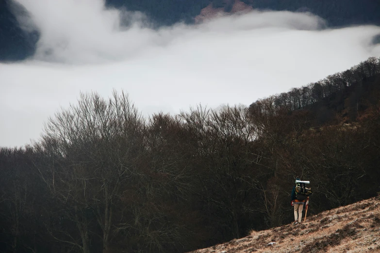 two people wearing backpacks walking up a steep hill