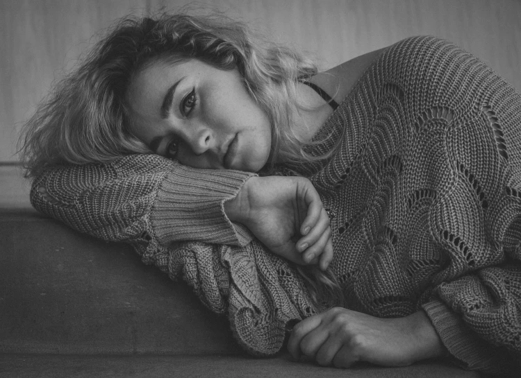 a woman laying on top of a couch next to a pillow