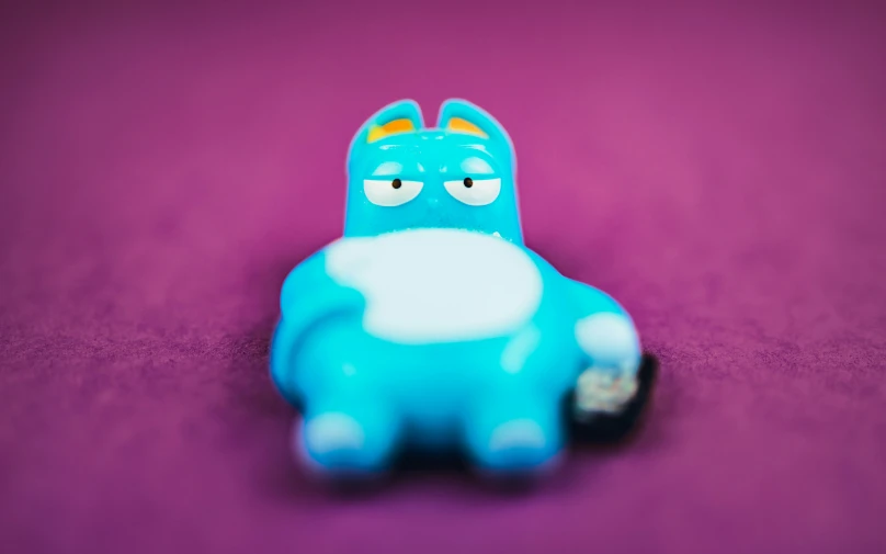 a little toy laying on top of a purple surface