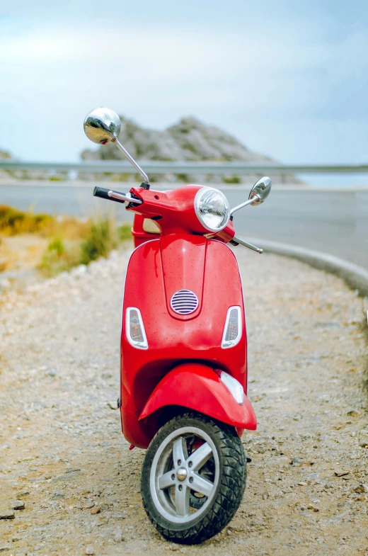 red scooter sits on the side of a curved road