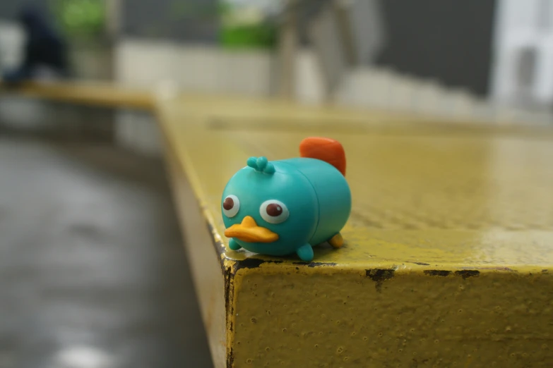 blue toy bird sitting on the edge of the wall