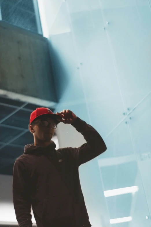 a young man is in the shadows holding his cap