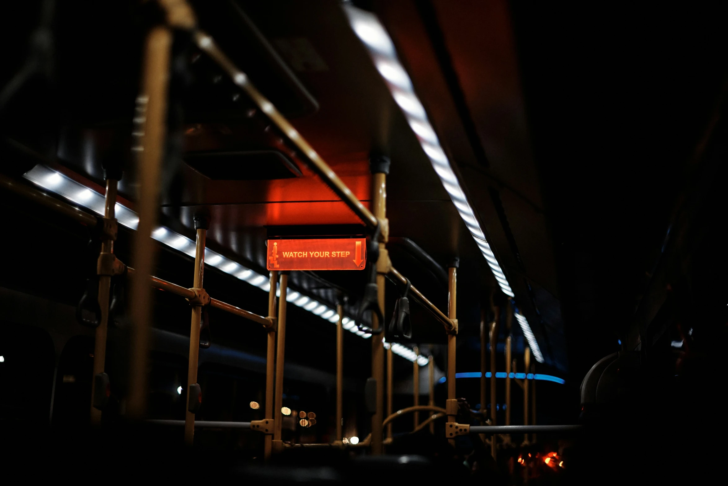 a neon red sign sitting in the dark by some poles