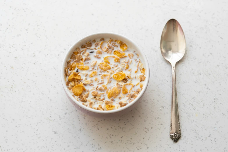 a white bowl of cereal and a spoon on a table