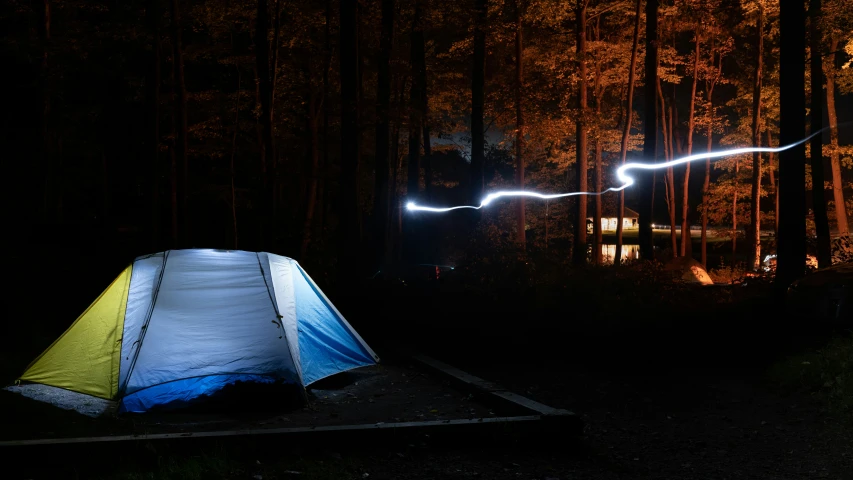 a tent in the forest is lit by two lights