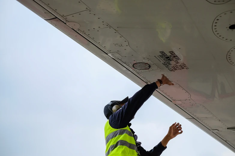 a man is dressed in a yellow safety vest standing outside of a plane