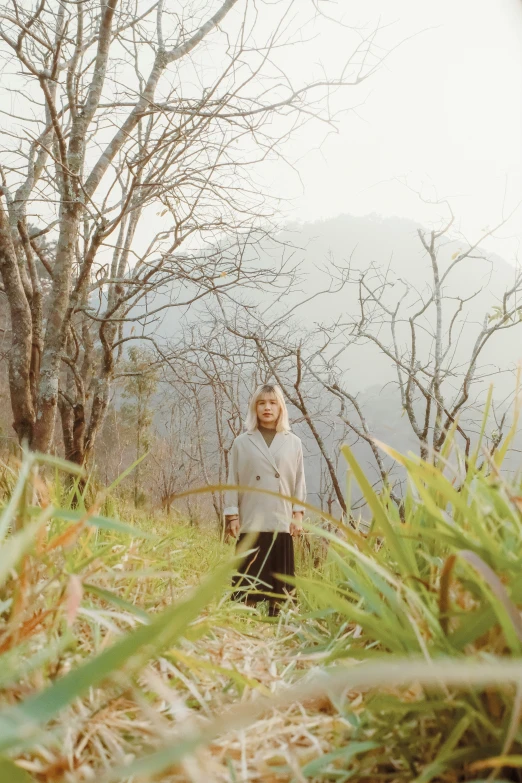 a woman is standing on the grass near the tree