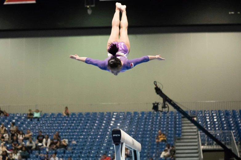 an olympic athlete jumps off the beam at a competition