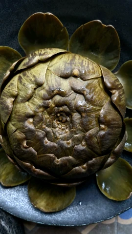 an artichoke on a plate with saucer on a table