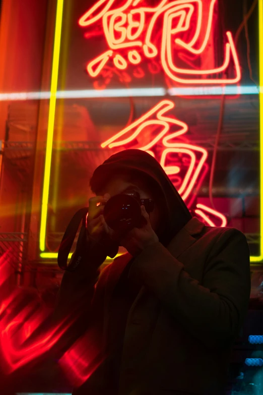 man taking pograph of neon display in urban setting