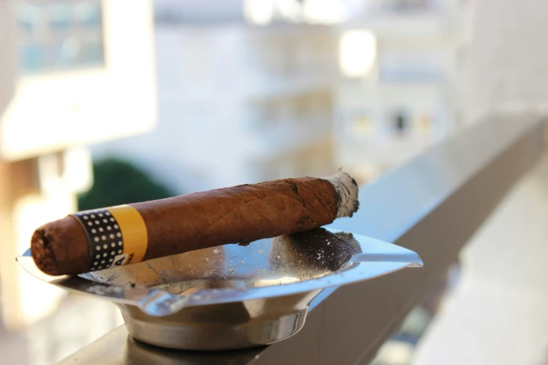 a cigar sits on top of a silver plate on a table