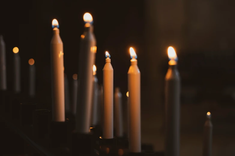 many white candles are lit in a dark room